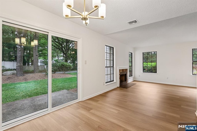 7 Eakens Ct, Mahwah, NJ 07430 - unfurnished living room featuring a chandelier, wood finished floors, a fireplace with flush hearth, and a textured ceiling