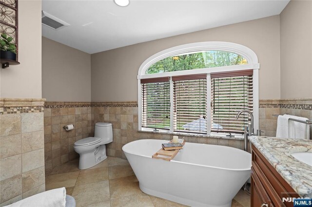 8 Fieldstone Dr, Kinnelon Borough, NJ 07405 - bathroom featuring tile walls, a soaking tub, a wainscoted wall, vanity, and tile patterned flooring