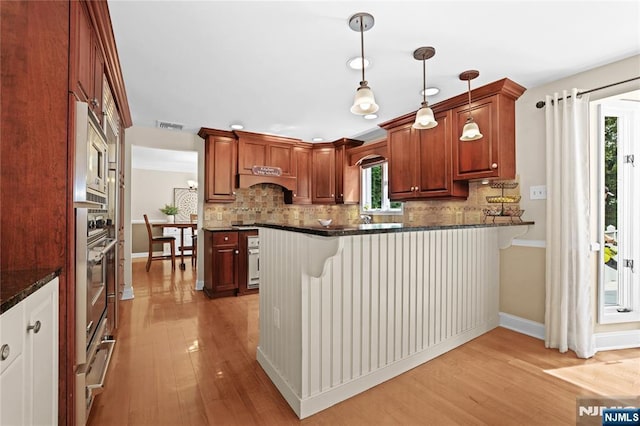 8 Fieldstone Dr, Kinnelon Borough, NJ 07405 - kitchen featuring a peninsula, light wood finished floors, tasteful backsplash, and a kitchen breakfast bar