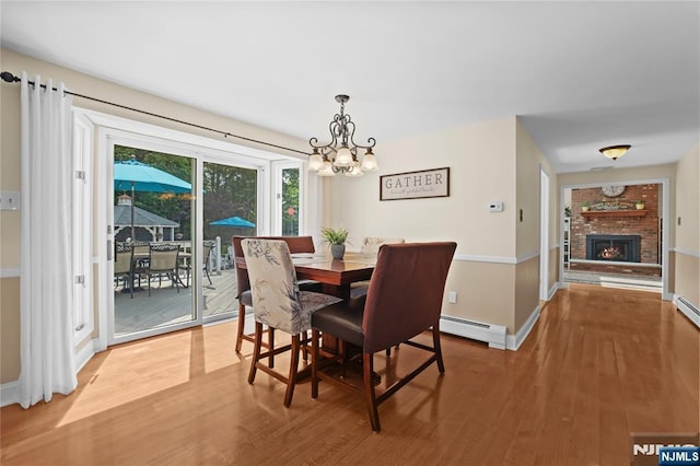 8 Fieldstone Dr, Kinnelon Borough, NJ 07405 - dining area with a chandelier, light wood-type flooring, a baseboard radiator, and a brick fireplace