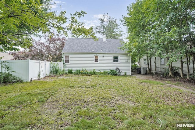 2 Ann St, Bloomingdale, NJ 07403 - rear view of house with a fenced backyard, a chimney, and roof with shingles