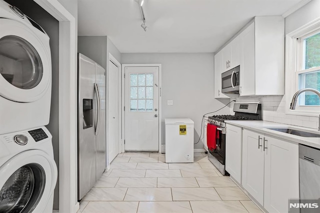 2 Ann St, Bloomingdale, NJ 07403 - kitchen featuring appliances with stainless steel finishes, stacked washer / dryer, rail lighting, white cabinetry, and light countertops