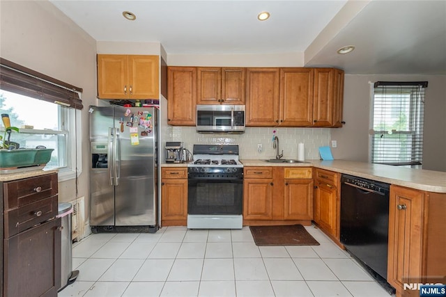 23 Preston St, Ridgefield Park, NJ 07660 - kitchen featuring appliances with stainless steel finishes, a peninsula, light countertops, brown cabinetry, and healthy amount of natural light