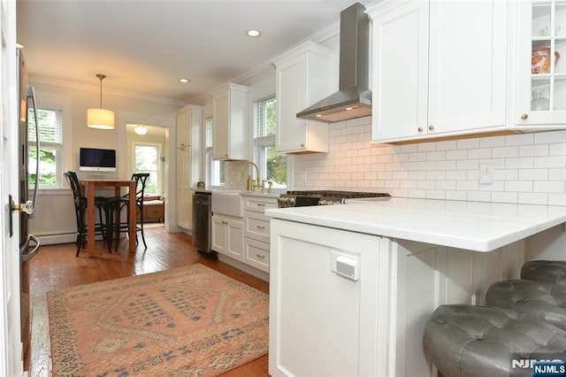 4 4th St, Park Ridge, NJ 07656 - kitchen with wall chimney range hood, ornamental molding, white cabinetry, wood finished floors, and light countertops