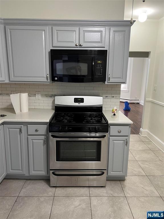121 W 14th, Bayonne, NJ 07002 - kitchen featuring black microwave, gray cabinetry, gas range, decorative backsplash, and ornamental molding