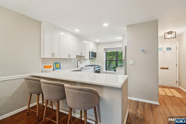 181 Long Hill Rd Unit H3, Little Falls, NJ 07424 - kitchen featuring dark wood-type flooring, light countertops, stainless steel appliances, white cabinetry, and tasteful backsplash