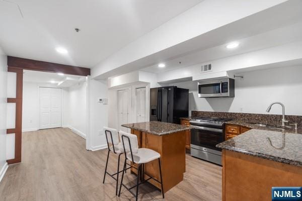 2608 Kennedy Blvd Unit 1, Union City, NJ 07087 - kitchen featuring appliances with stainless steel finishes, a breakfast bar, brown cabinetry, light wood-style floors, and recessed lighting