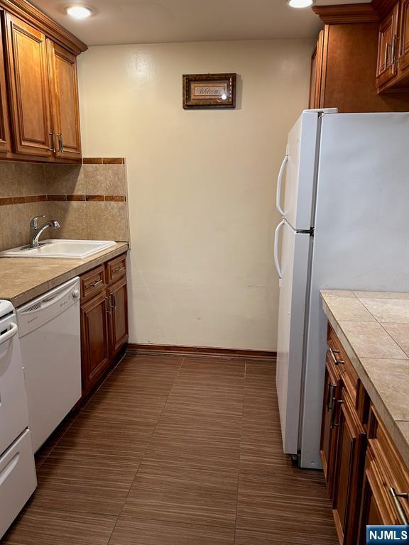 111 Mulberry St Unit 1418, Newark, NJ 07102 - kitchen featuring white appliances, backsplash, brown cabinets, light countertops, and recessed lighting
