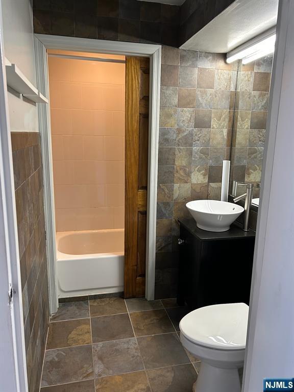 111 Mulberry St Unit 1418, Newark, NJ 07102 - bathroom with tile walls, vanity, and stone finish floors