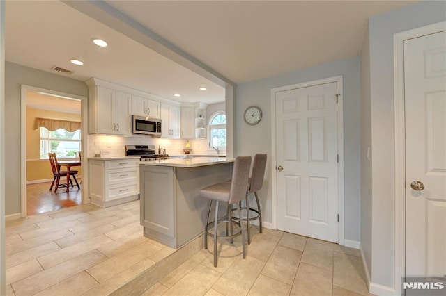 306 Boulevard, Pequannock Township, NJ 07444 - kitchen featuring stainless steel appliances, light countertops, backsplash, a kitchen bar, and white cabinets