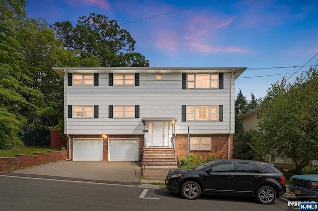132 17th St, Prospect Park, NJ 07508 - view of front of house featuring brick siding, a garage, and asphalt driveway