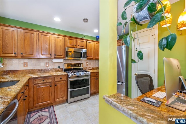 143 Summit Rdg, Pompton Lakes, NJ 07442 - kitchen featuring stainless steel appliances, decorative backsplash, light tile patterned floors, brown cabinetry, and light stone countertops