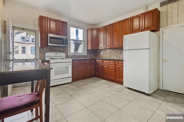223 N 6th St, Newark, NJ 07107 - kitchen featuring white appliances, tasteful backsplash, dark countertops, light tile patterned floors, and dark brown cabinets