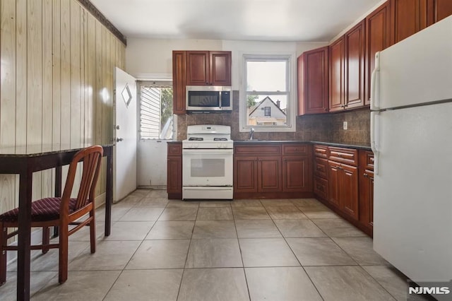 223 N 6th St, Newark, NJ 07107 - kitchen with white appliances, backsplash, reddish brown cabinets, and wooden walls