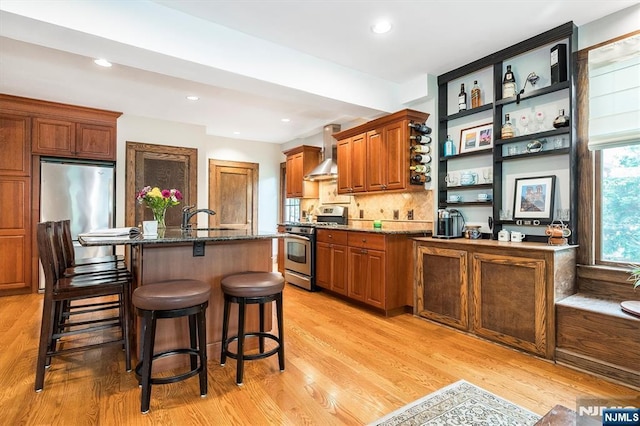 34 Harding Rd, Glen Rock, NJ 07452 - kitchen with appliances with stainless steel finishes, wall chimney range hood, light wood-type flooring, dark stone counters, and recessed lighting