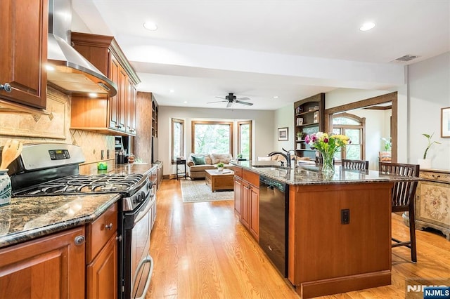 34 Harding Rd, Glen Rock, NJ 07452 - kitchen featuring gas range, wall chimney exhaust hood, black dishwasher, a breakfast bar, and light wood-style floors