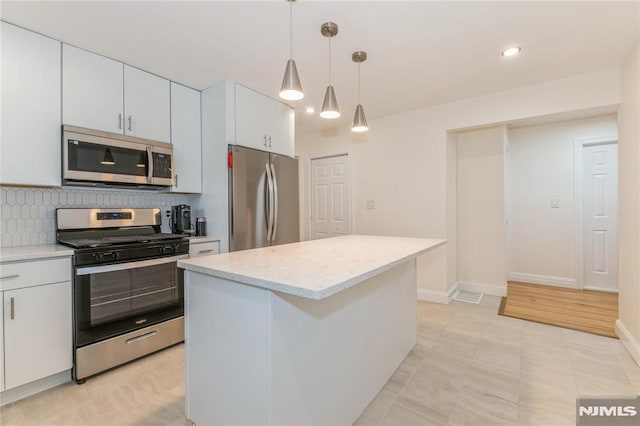 63 E Midland Ave, Kearny, NJ 07032 - kitchen featuring stainless steel appliances, tasteful backsplash, a kitchen island, pendant lighting, and white cabinets