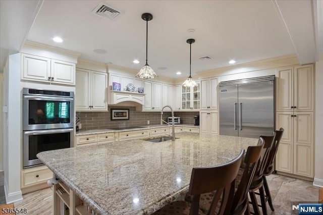 4 Lowell Ct Unit 704, Teaneck, NJ 07666 - kitchen featuring stainless steel appliances, a breakfast bar area, decorative backsplash, a center island with sink, and light stone counters