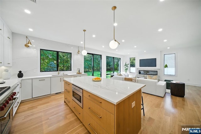 30 Benjamin Rd, Tenafly, NJ 07670 - kitchen with stainless steel appliances, light wood-style flooring, a kitchen island, recessed lighting, and white cabinetry