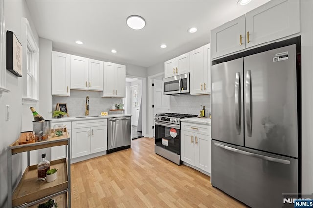 422 Davis Ave, Kearny, NJ 07032 - kitchen with appliances with stainless steel finishes, light countertops, backsplash, light wood-style flooring, and white cabinets