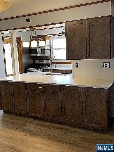 297 Terhune Dr, Wayne, NJ 07470 - kitchen featuring stainless steel range with gas cooktop, wood finished floors, dark brown cabinets, light countertops, and crown molding