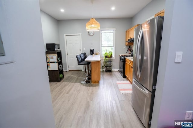 95 Mount Prospect Ave, Newark, NJ 07104 - kitchen featuring freestanding refrigerator, black range with gas stovetop, light wood-style floors, a breakfast bar area, and light countertops