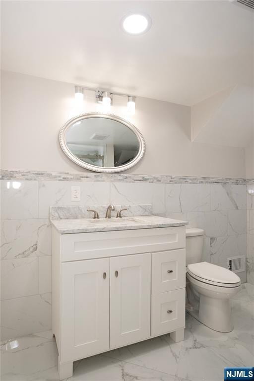 35 3rd Ave, Little Falls, NJ 07424 - bathroom featuring marble finish flooring, tile walls, vanity, and a wainscoted wall