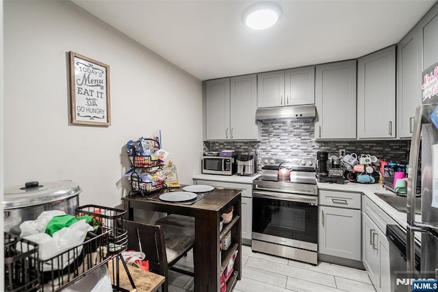 188 Park St, East Orange, NJ 07017 - kitchen featuring appliances with stainless steel finishes, gray cabinets, under cabinet range hood, light countertops, and decorative backsplash
