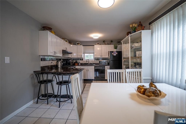 72 N Dr, Rochelle Park, NJ 07662 - kitchen with black appliances, under cabinet range hood, backsplash, a peninsula, and light tile patterned floors