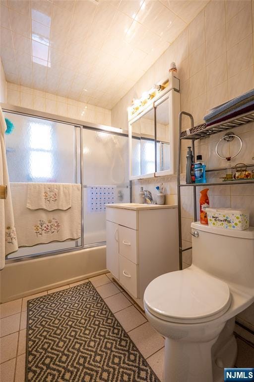 72 N Dr, Rochelle Park, NJ 07662 - bathroom featuring vanity, tile walls, combined bath / shower with glass door, and tile patterned floors