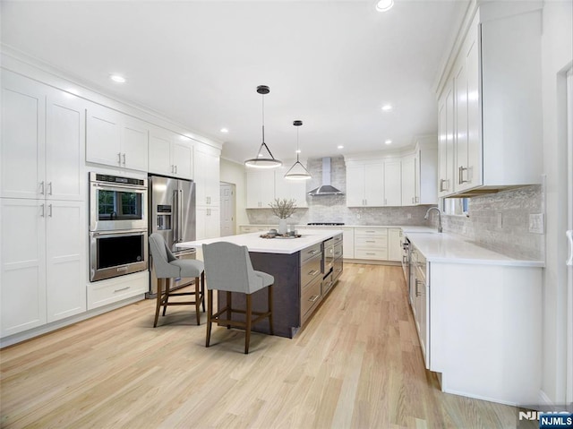 345 Creek Bed Rd, Mountainside, NJ 07092 - kitchen featuring wall chimney range hood, stainless steel appliances, a breakfast bar, a kitchen island, and light countertops