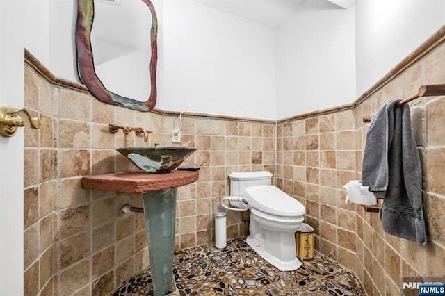 82 Jackson Dr, Cresskill, NJ 07626 - half bathroom featuring tile walls, wainscoting, and stone finish floors