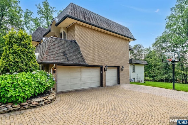 82 Jackson Dr, Cresskill, NJ 07626 - view of side of property featuring brick siding, decorative driveway, a high end roof, and mansard roof