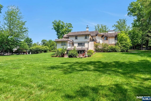 82 Jackson Dr, Cresskill, NJ 07626 - back of house featuring stucco siding, a yard, and a chimney