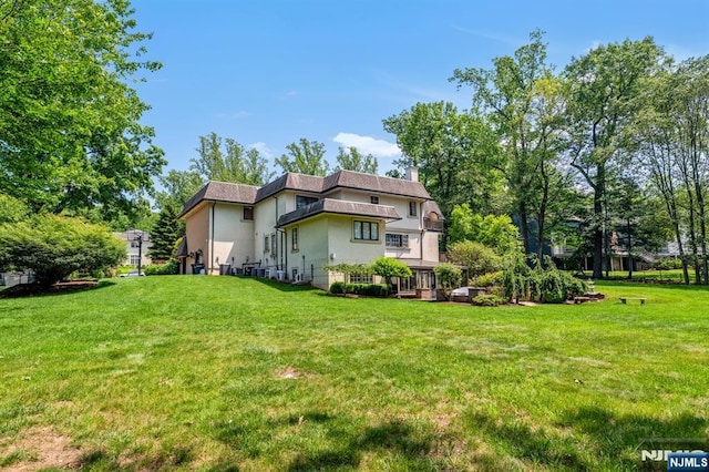 82 Jackson Dr, Cresskill, NJ 07626 - rear view of house featuring stucco siding, a chimney, and a lawn