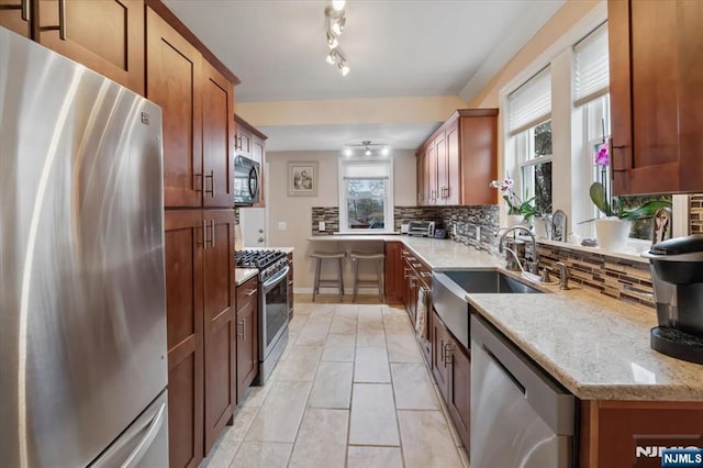 460 River Rd, Bogota, NJ 07603 - kitchen with appliances with stainless steel finishes, decorative backsplash, light stone counters, and brown cabinets