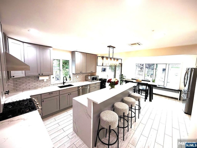 45 Highland Ave, Emerson, NJ 07630 - kitchen featuring stainless steel appliances, tasteful backsplash, a kitchen breakfast bar, gray cabinetry, and a center island