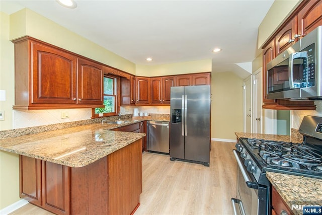 40 Lake Dr, Wayne, NJ 07470 - kitchen featuring stainless steel appliances, a peninsula, light wood-type flooring, light stone counters, and decorative backsplash