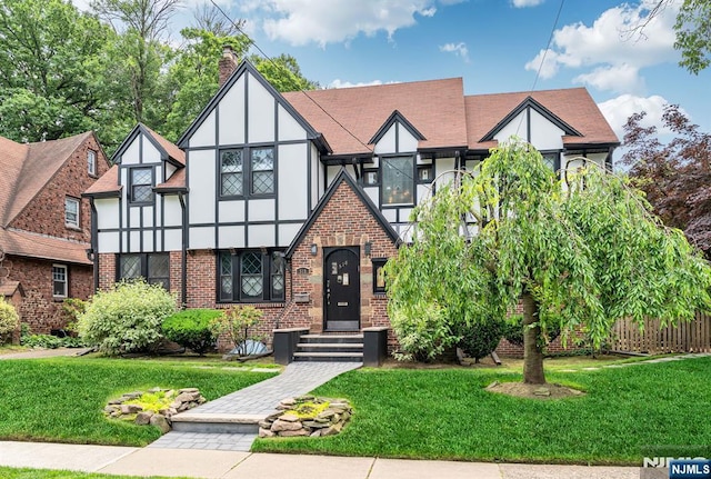 518 Standish Rd, Teaneck, NJ 07666 - english style home with stucco siding, a front lawn, a chimney, and brick siding