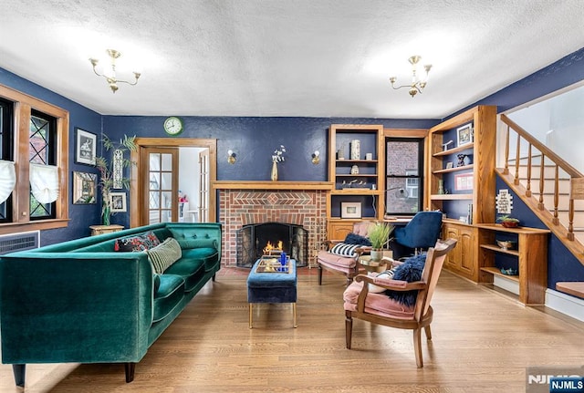 518 Standish Rd, Teaneck, NJ 07666 - living room with wood finished floors, a textured ceiling, a chandelier, stairway, and a fireplace