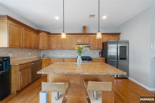 87 Centre St Unit 2, Nutley, NJ 07110 - kitchen featuring appliances with stainless steel finishes, under cabinet range hood, light wood finished floors, decorative backsplash, and brown cabinetry