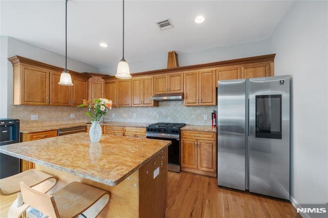 87 Centre St Unit 2, Nutley, NJ 07110 - kitchen with stainless steel appliances, under cabinet range hood, light wood-type flooring, brown cabinetry, and decorative light fixtures