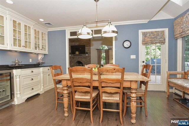 581 Eder Ave, Wyckoff, NJ 07481 - dining area featuring beverage cooler, dark wood finished floors, bar, crown molding, and a fireplace