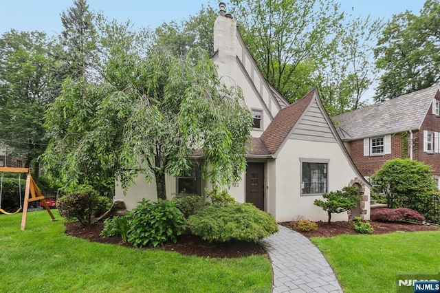 122 Howard Ter, Leonia, NJ 07605 - view of front of property with stucco siding, a playground, a front yard, and a chimney