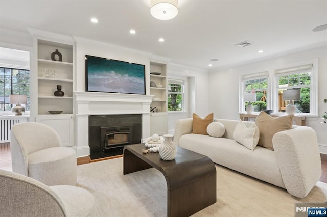 122 Howard Ter, Leonia, NJ 07605 - living room featuring wood finished floors, ornamental molding, recessed lighting, built in shelves, and radiator heating unit