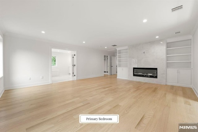 22 Northwood Ave, Demarest, NJ 07627 - unfurnished living room with built in shelves, crown molding, heating unit, a tile fireplace, and light wood-style flooring