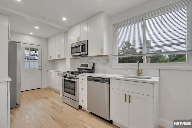 115 Wilson Ave, Rutherford, NJ 07070 - kitchen featuring appliances with stainless steel finishes, light countertops, white cabinetry, light wood finished floors, and decorative backsplash