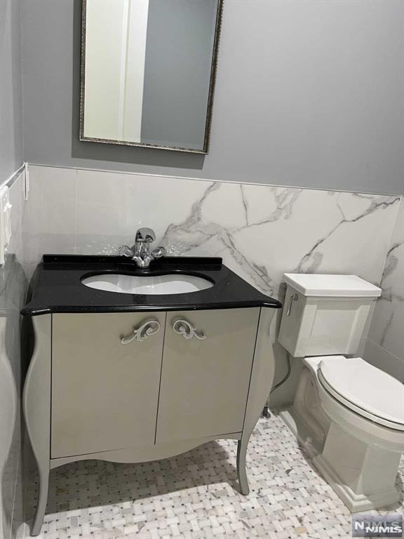 275 Gorden Dr, Paramus, NJ 07652 - half bathroom with tile walls, vanity, and a wainscoted wall