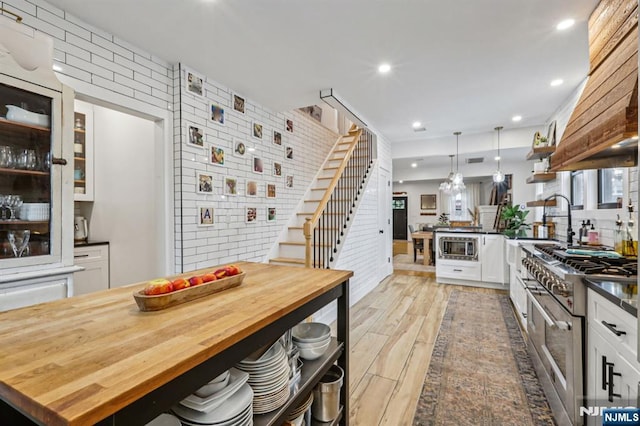 21 Mountainview Ave, Nutley, NJ 07110 - kitchen with white cabinetry, appliances with stainless steel finishes, light wood finished floors, a kitchen breakfast bar, and a peninsula