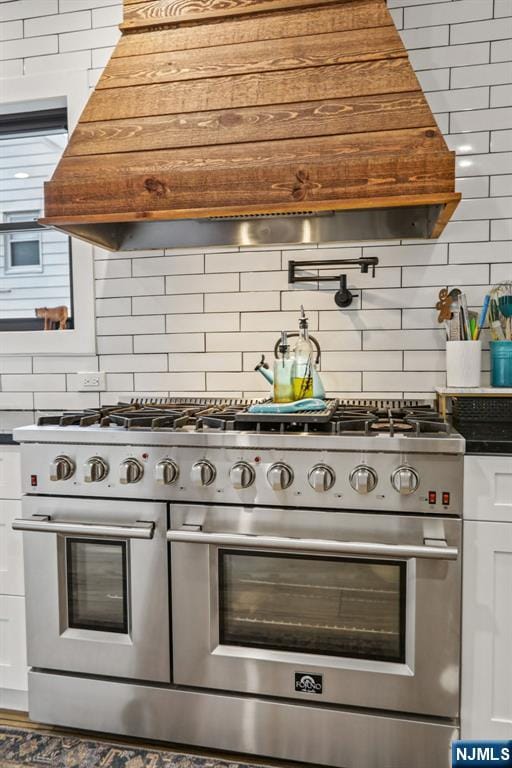 21 Mountainview Ave, Nutley, NJ 07110 - kitchen view of stainless steel range, pot filler, backsplash, white cabinetry, and premium range hood